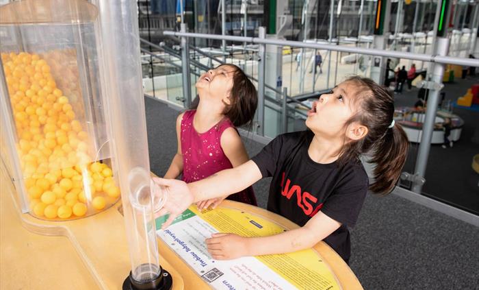 Two children look up at the Probability Pattern exhibit in amazement.